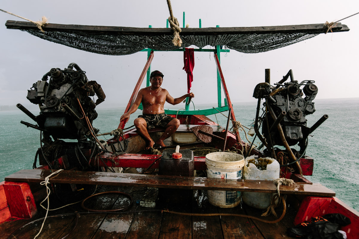 Long boat captain in heavy rain at sea in Sihanoukville