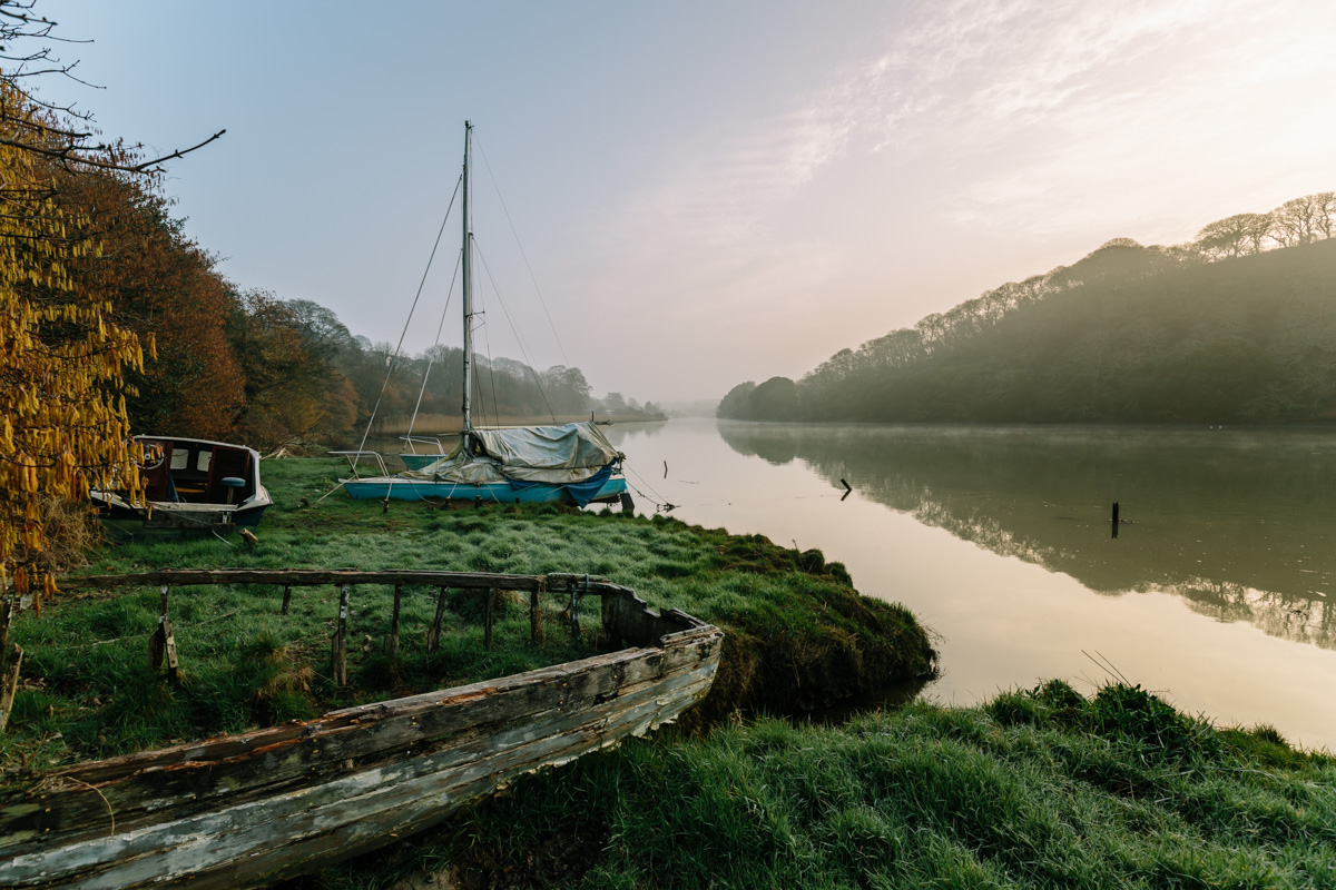 A boat decays in front of a misty morning on the river Truro