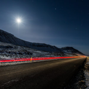 A car’s tail-lights disapears into the night